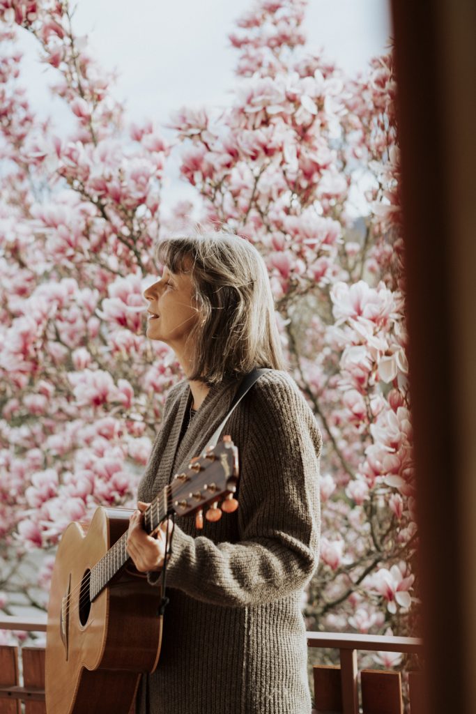 Songwriterin Dorothe Wilmanns mit Gitarre vor Magnolienbaum zu Song Nummer 9 Du sollst leben